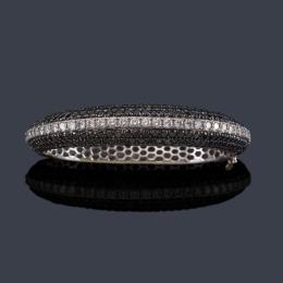 Lote 2419<br>Pulsera rígida con banda central de brillantes incoloros y pavé de diamantes negros en ambos lados sobre montura de oro blanco de 18K.