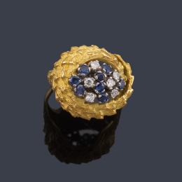 Lote 2130<br>Anillo con centro de zafiros y brillantes sobre montura con diseño vegetal texturizado de oro amarillo de 18K.