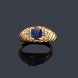 Lote 2444<br>Anillo con zafiro talla oval de aprox. 0,70 ct con brillantes en ambos lados en montura gallonada de oro amarillo de 18K.