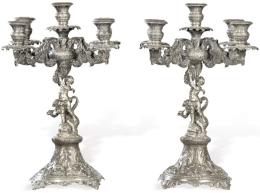 Lote 1160: Pareja de candelabros de plata española sin punzonar.<br>Con cinco brazos de luz y vástago con dos amorcillos alados sobre un pez, uno de ellos con trompeta en forma de concha.