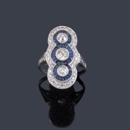 Lote 2081: Anillo lanzadera con tres diamantes talla antigua de aprox. 1,10 ct en total con doble orla de zafiros calibrados y brillantes de aprox. 0,65 ct en total.