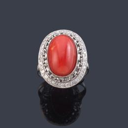 Lote 2090: Anillo con centro de coral talla cabujón con orla de brillantes de aprox. 0,60 ct en total.