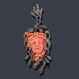 Lote 2395: Colgante con motivo de Medusa realizada con pieza de Coral tallada de aprox. 55,45 ct enriquecido con múltiples cabezas de serpientes con diamantes de aprox. 3,60 ct en total y un rubí en montura de plata.