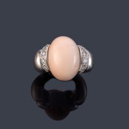 Lote 2459: Anillo con pieza de coral rosa talla cabujón con bandas de brillantes en montura de oro blanco de 18K.