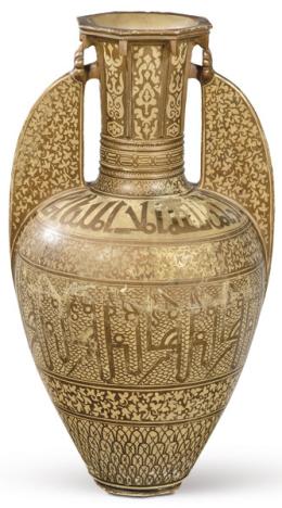 Lote 1013: Jarrón o vaso de la Alhambra en cerámica esmaltada con reflejo metálico cobrizo con decoración de elementos vegetales y escritura cúfica. Asas planas y boca estrecha. <br>h. 1900