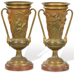 Lote 1504: Pareja de copas con asas de bronce dorado, Francia S. XIX<br>Con figuras clásicas en relieve y base de mármol rojo.